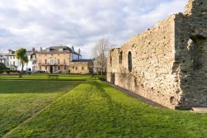 an old stone wall with a park and buildings at The Kings Arms in Christchurch