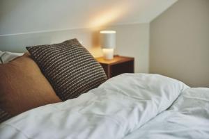 a bed with a pillow and a lamp on a night stand at Bris Apartments in Haugesund