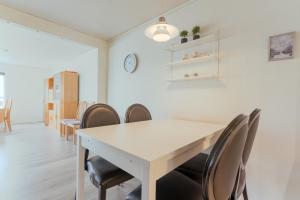 a dining room with a white table and chairs at Spacious Basement Apartment with Mountain Views in Streymnes