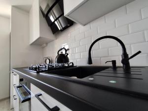 a kitchen with a sink and a black counter top at Sweet Apartament 6 osobowy in Płock