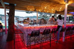 a bar with people sitting at it in a restaurant at Zelena Punta Resort in Kukljica