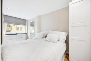a white bedroom with a large white bed with pillows at Modern apartment in Bergen city centre in Bergen