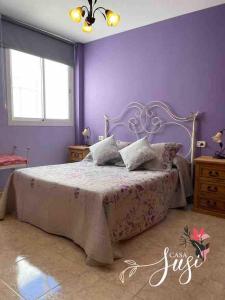 a bedroom with a large bed with purple walls at Casa Susi in Tazacorte
