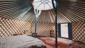 a room with a bed in a yurt with a clock at Cosy yurt at a nature retreat in Sequoia N Forest in Miramonte