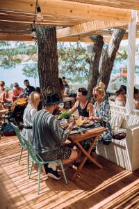 a group of people sitting at a table eating food at Zelena Punta Resort in Kukljica