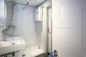 a white bathroom with a shower and a sink at Hotel Die Port van Cleve in Amsterdam