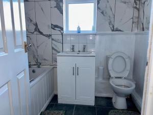 Un baño con inodoro, lavabo y ventana. en Room A at StanBros, en Coseley