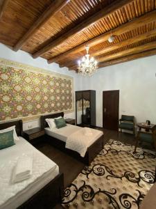 a bedroom with two beds and a chandelier at Mukhlisabegim Hotel in Bukhara