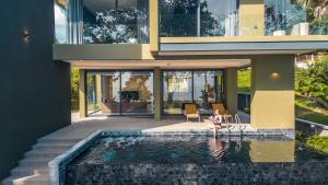 a woman sitting in a chair next to a swimming pool at Merbrisa Rayong poolvilla 4BR - Ao khai beachfront in Mae Pim