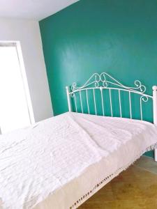a white bed in a room with a green wall at Mountain Lodge in La Laura