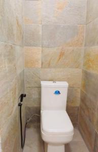 a white toilet in a bathroom with a tiled wall at Mountain Lodge in La Laura