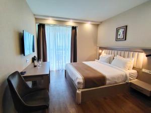 a hotel room with a bed and a desk and a chair at Del Mare Aparthotel in Batumi +47 photos