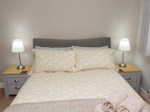 a bedroom with a bed with two nightstands and two lamps at Assisi Apartment in Alnmouth