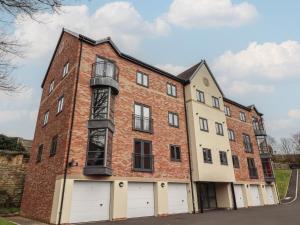 an old brick building with white doors and a balcony at Assisi Apartment in Alnmouth