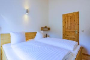 a bedroom with a bed with white sheets and a door at MöwenKieker mit Terrasse im Ferienpark Silz in Silz