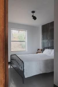 a bedroom with a white bed with a window at Secluded rustic 2-bedroom cabin on nature retreat in Miramonte