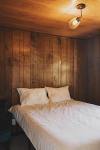 a bedroom with a white bed with wooden walls at Secluded rustic 3-bedroom cabin on private land in Miramonte
