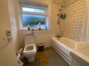 a bathroom with a toilet and a tub and a window at Redhill and Gatwick in Redhill