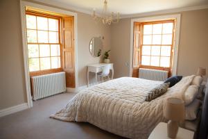 a bedroom with a large bed and two windows at Starbright Cottage in Peebles