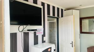 a living room with a flat screen tv on a wall at sediba guest house in Krugersdorp