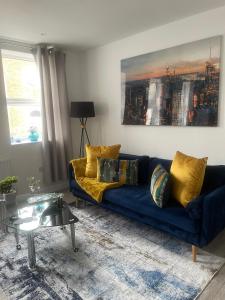 a living room with a blue couch with yellow pillows at Charming 2- Bedroom Apartment in Watford