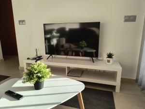 a living room with a large television on a white table at vera playa atico balcón al mediterráneo in Vera