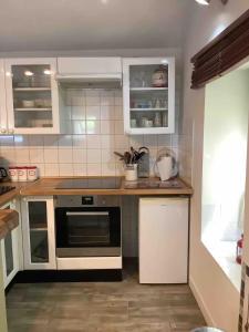 eine Küche mit weißen Schränken und einem Herd mit Backofen in der Unterkunft Woodland Cottage in Faux-la-Montagne