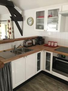 eine Küche mit Spüle und einer Uhr an der Wand in der Unterkunft Woodland Cottage in Faux-la-Montagne