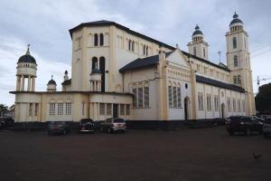 a large white building with cars parked in a parking lot at Chic studio with parking near the airport in Douala