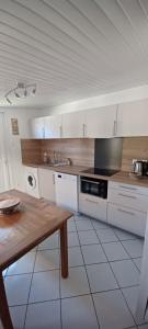 a kitchen with white cabinets and a wooden table at Chez Isa et JP in Soulac-sur-Mer