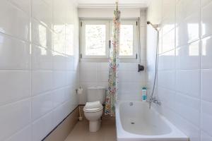 a bathroom with a toilet and a tub and a window at Exclusiva Terraza y parking a 5 min de Bilbao in Bilbao +19 photos