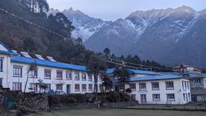 a large white building with mountains in the background at Himalaya Lodge & Restaurant in Lukla