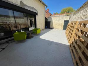 a patio with two green chairs and a table at Les HIRONDELLES CHAMBRES HOTES 10 PERSONNES in Festubert