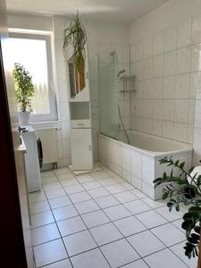 a white tiled bathroom with a tub and a window at Haus in Ossendorf Köln in Cologne