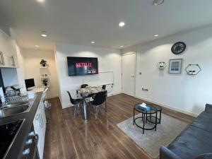 a kitchen and living room with a table and a tv at NumberOne - PINK - MediaCityUK in Manchester
