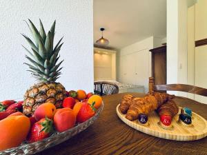 two plates of fruit and croissants on a wooden table at LX112 Balcon, jardin, piscine, résidence privée in Mandelieu-la-Napoule +7 photos