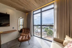 a bedroom with a chair and a large window at New Time 715 - Luxo à beira-mar da Pajuçara in Maceió +53 photos