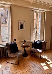 a living room with two chairs and a table and windows at L'Hotel Particulier in Louhans