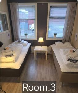 two beds in a room with two windows at Koselig rom i sentrum Gratis Wifi og Parkering Rom 3 1 etg in Narvik