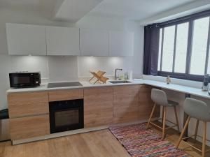 a kitchen with white cabinets and a stove top oven at La Maisonnette Notre Dame - Terrasse privative - Hypercentre - 50m Bords de Loire - 4 personnes in Orléans