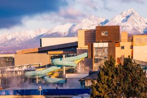 a building with slides in front of snowy mountains at Dovolenkový dom Ela pets friendly in Poprad