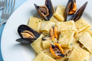 a white plate of food with mussels and seafood at Hotel Albatros in Ischia