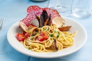 a plate of pasta with shrimp and vegetables on a table at Hotel Albatros in Ischia
