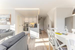 a white kitchen and living room with a table and chairs at Appartement Meeresleuchten - Nicolinenhof in Wenningstedt