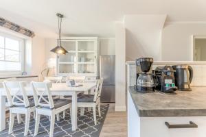 a kitchen with a white table and white chairs at Appartement Lachmöwe - Nicolinenhof in Wenningstedt