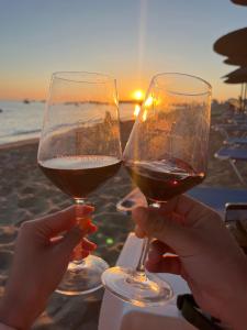 two people holding glasses of wine on the beach at Papiri Beach in Agios Georgios