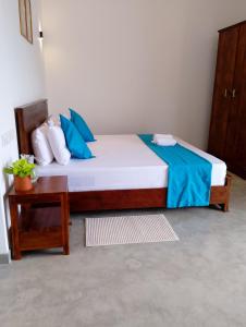 - une chambre avec un lit doté d'oreillers bleus et d'une table dans l'établissement Crush River Villa Hikkaduwa, à Hikkaduwa