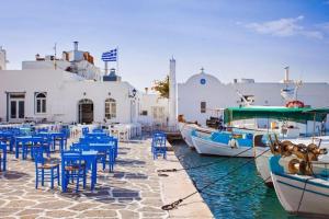 a group of tables and chairs and boats in the water at Rodis Cycladic Holiday House in Naousa