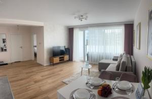 Una sala de estar con un sofá, una mesa y un televisor. en Apartament Sunset 14, en Ustronie Morskie