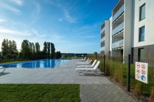 una fila de sillones blancos junto a un edificio en Apartament Sunset 14, en Ustronie Morskie